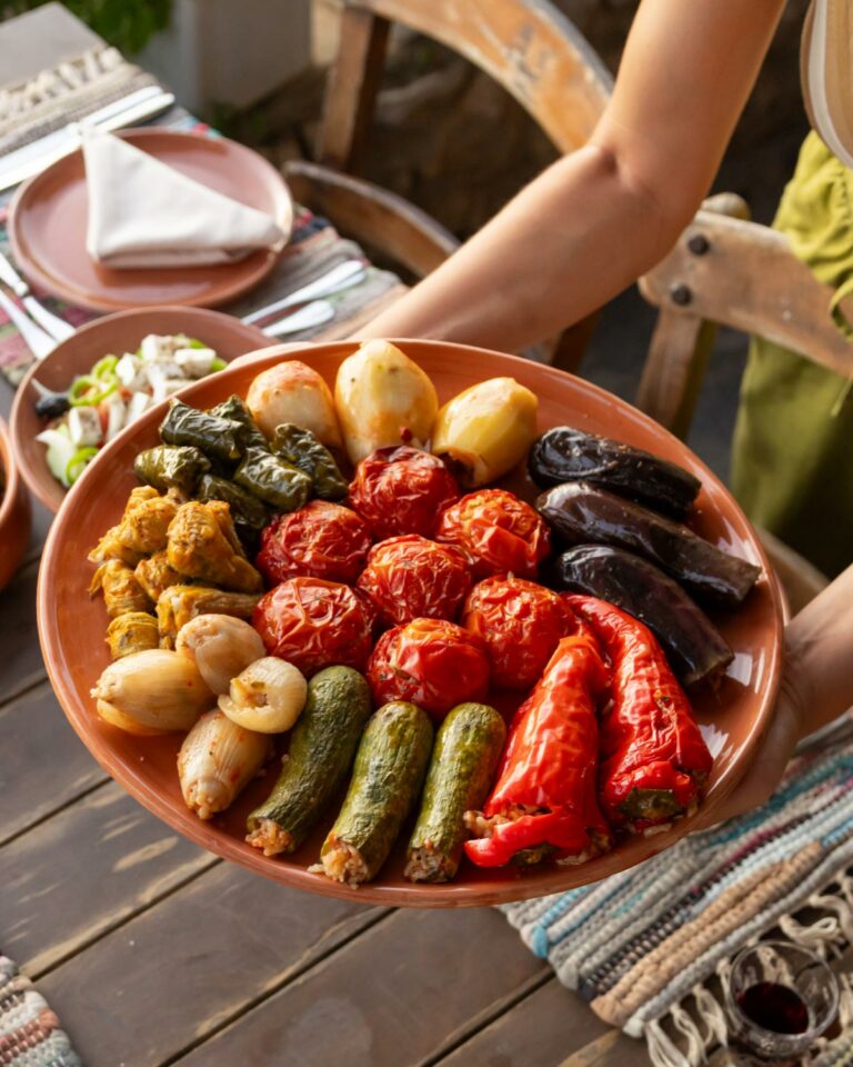 Rustic platter of roasted seasonal vegetables, including tomatoes, peppers, zucchini and onions.