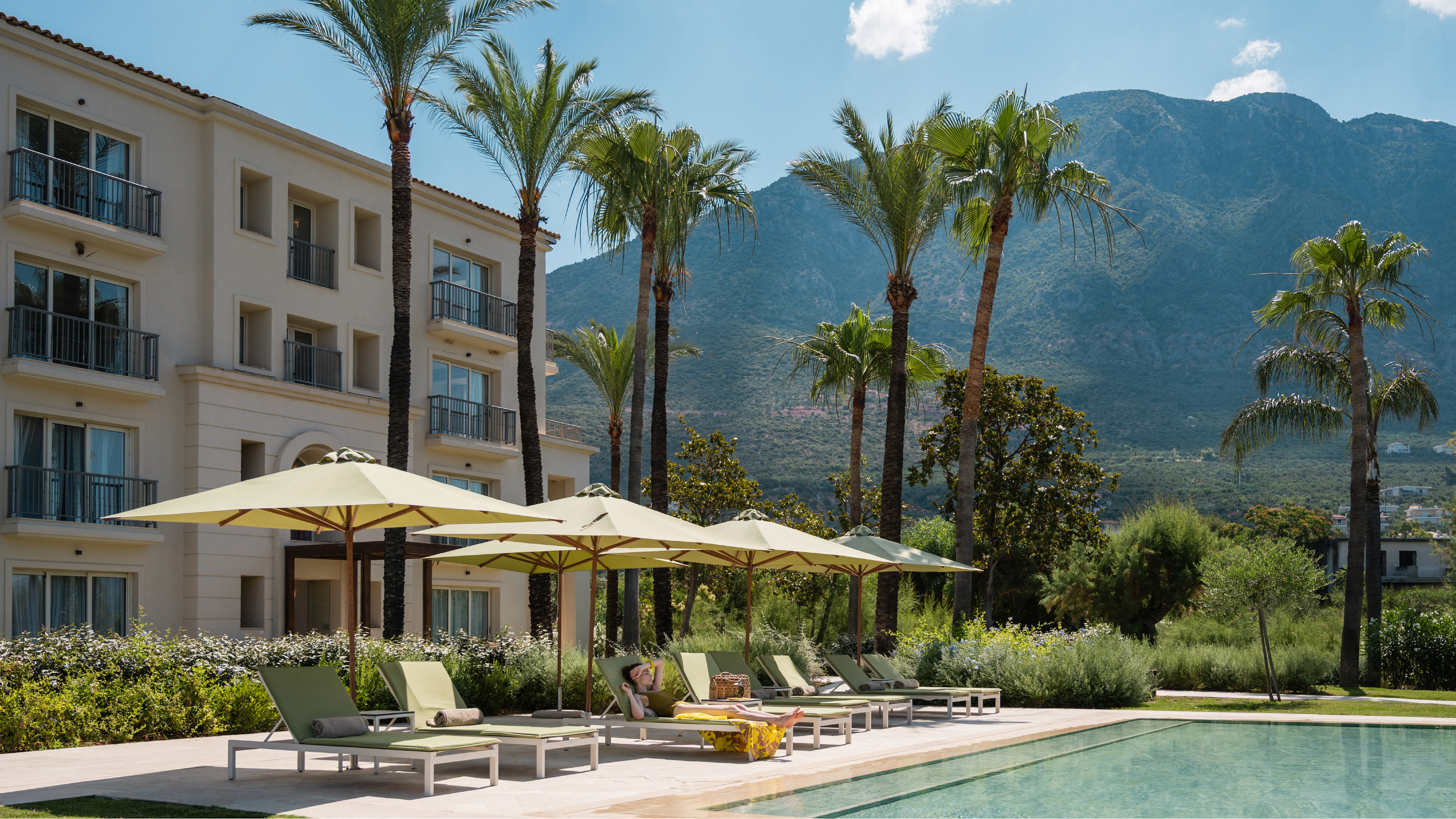 Filoxenia Kalamata resort pool area with palm trees and mountain views