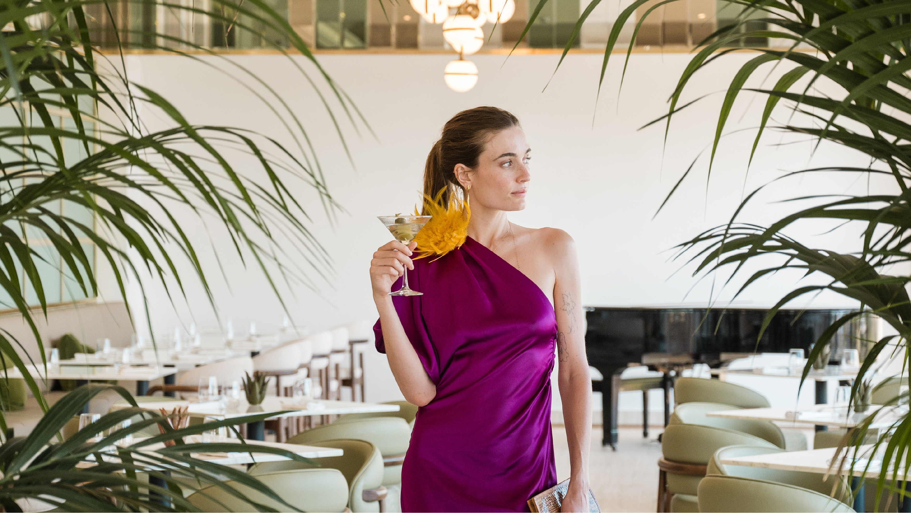Woman in a magenta dress holding a cocktail at Grecotel Filoxenia