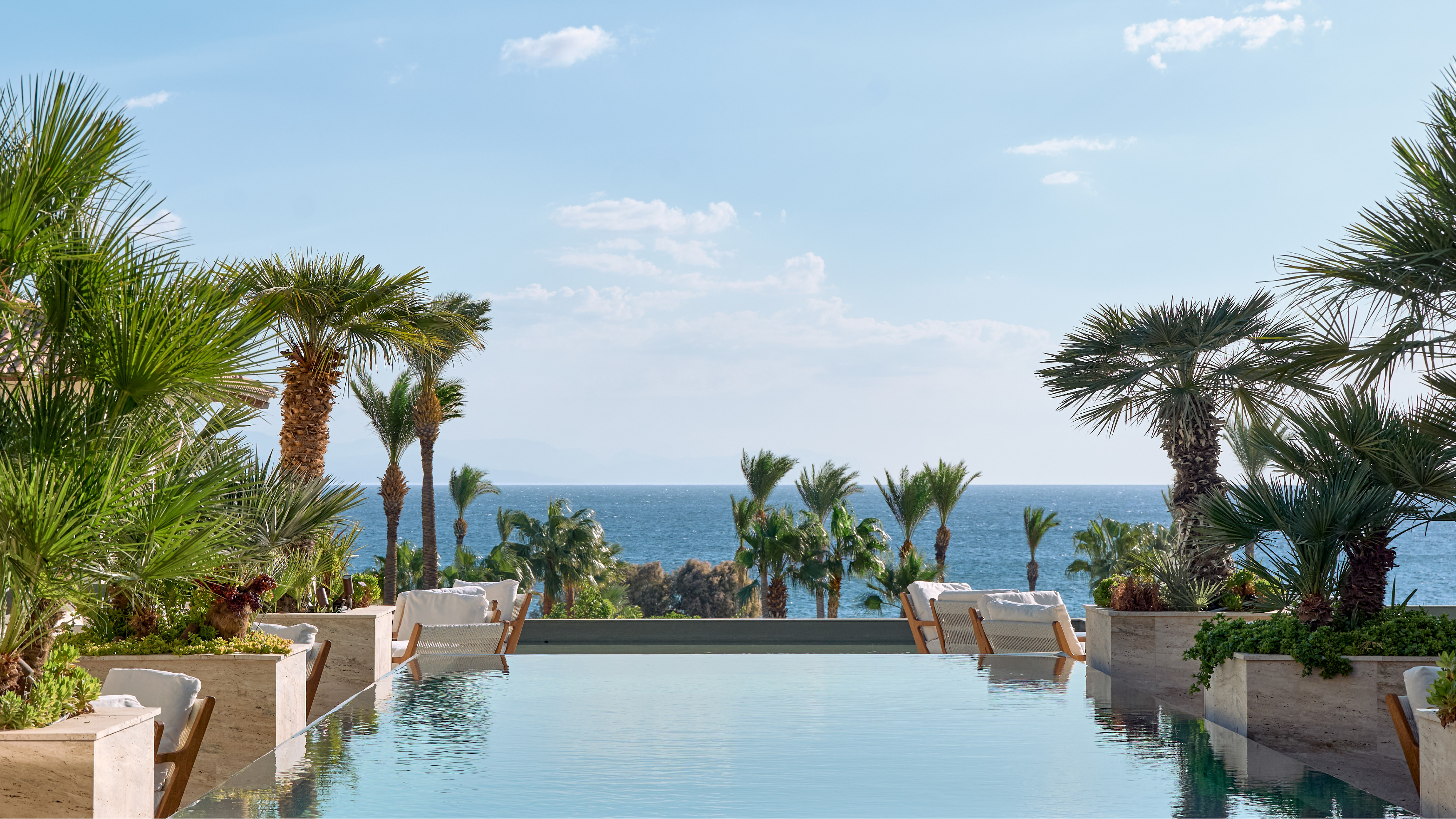 Tropical island resort view with palm trees, pools, and beachfront at Grecotel LUXME Kos