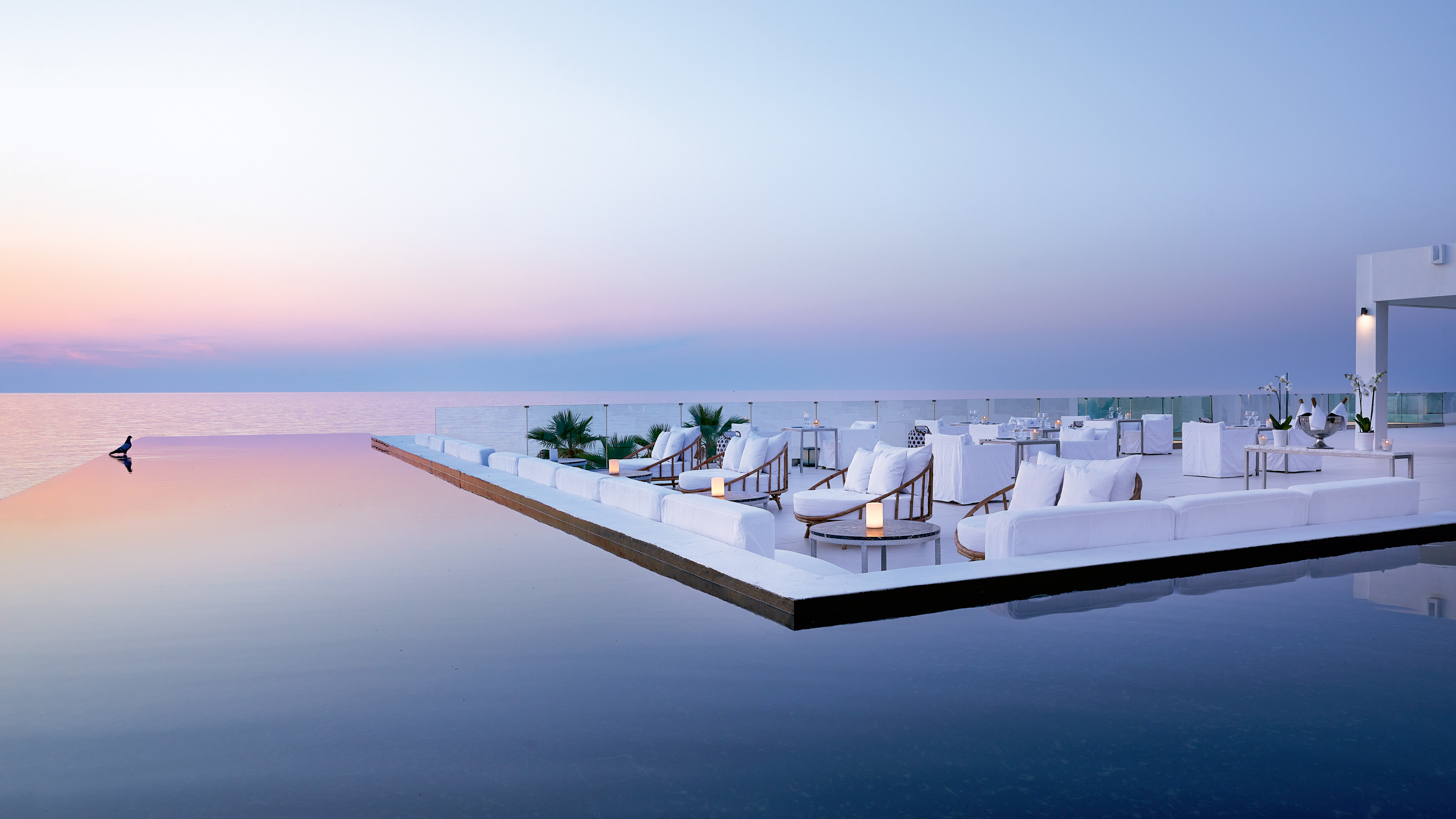 Grecotel LUXME White Crete infinity pool with sea view and white outdoor seating.