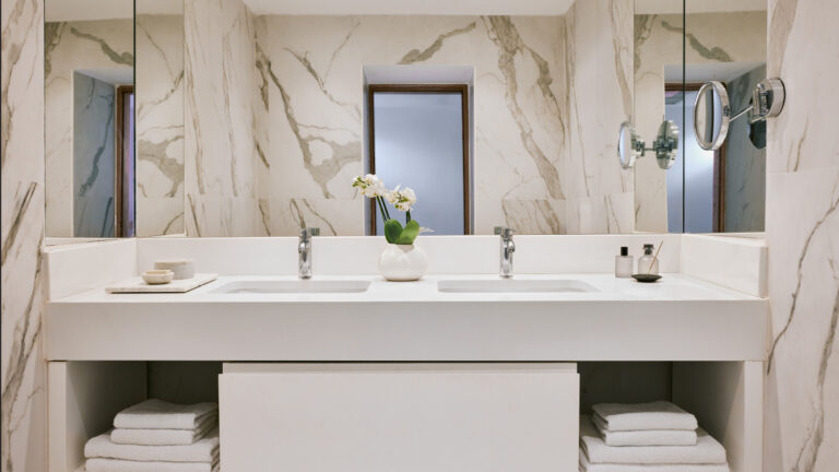 Grecotel LUXME White Crete Junior Suite bathroom with double vanity and marble walls.