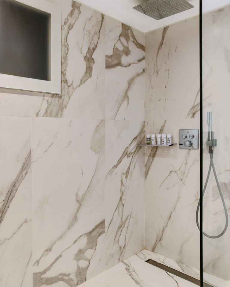 Grecotel LUXME White Crete Open-plan Suite bathroom with marble walls and walk-in shower.