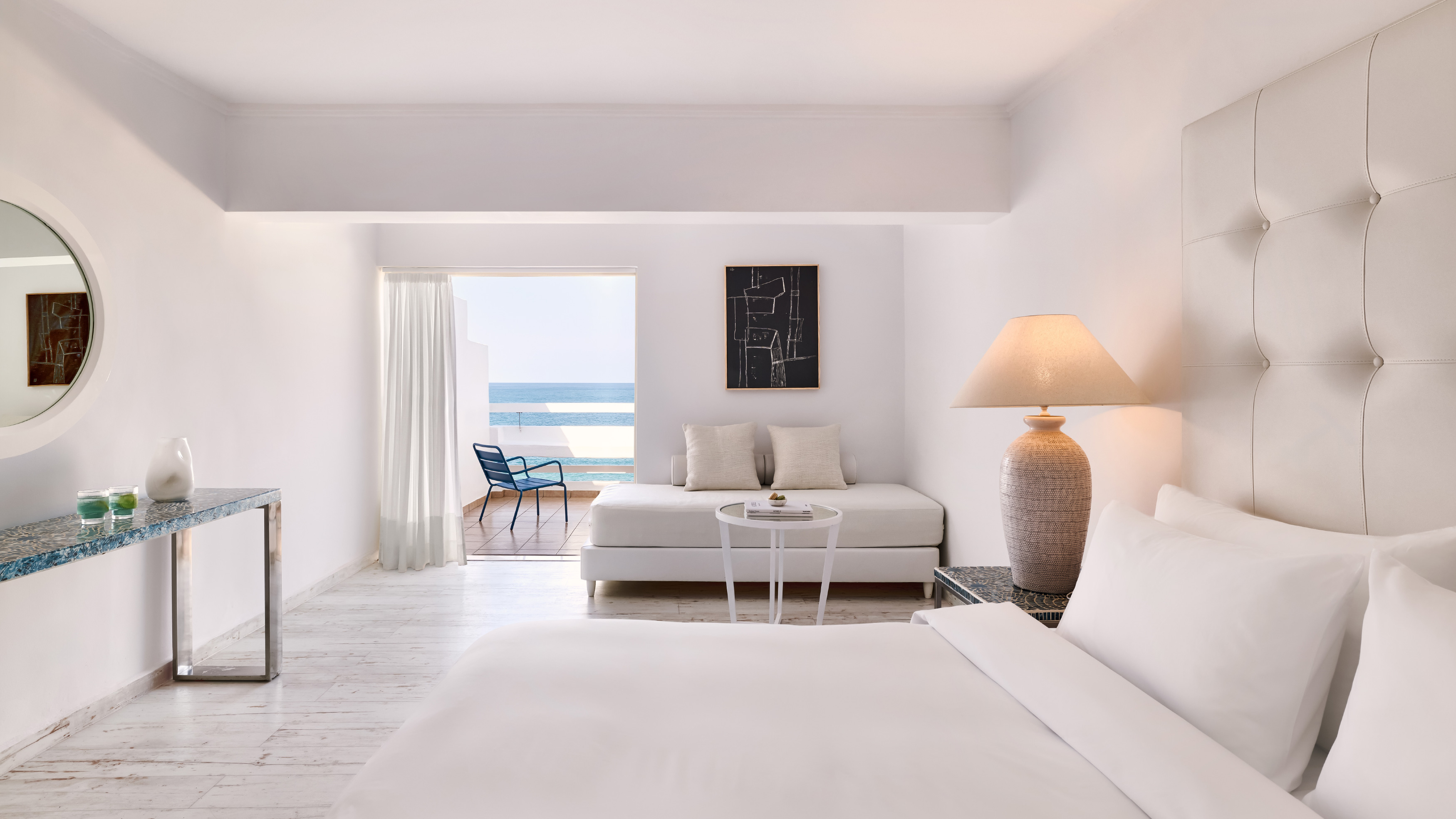 Grecotel LUXME White Crete Open-plan Suite with king bed, sofa and sea view.