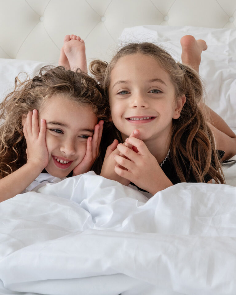 Children relaxing on a bed in a Grecotel LUXME White Crete Family Guestroom.