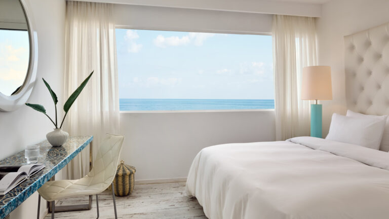 Grecotel LUXME White Crete Grand Family Suite bedroom with sea view and upholstered headboard.