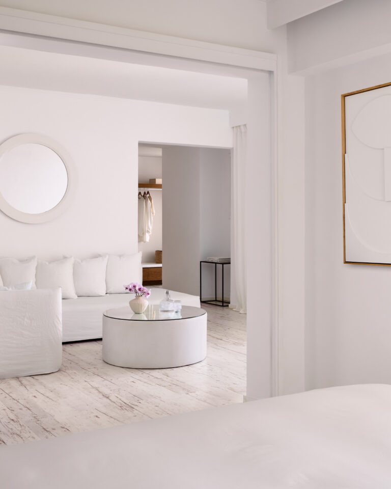 Grecotel LUXME White Crete Grand Family Suite living area with sofa, round table and artwork.