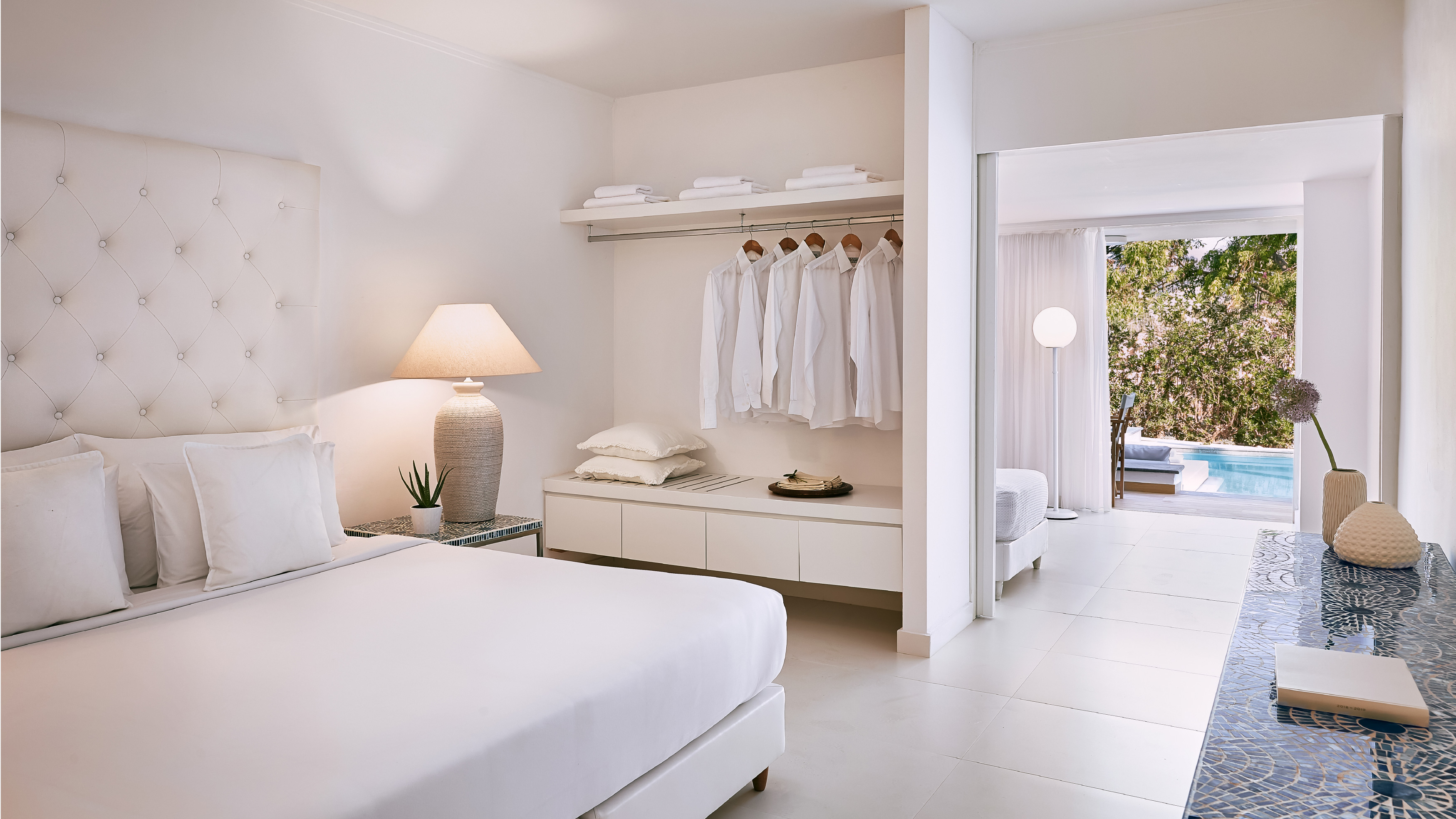 Grecotel LUXME White Crete Swim-up Family Guestroom bedroom with king bed and pool view.