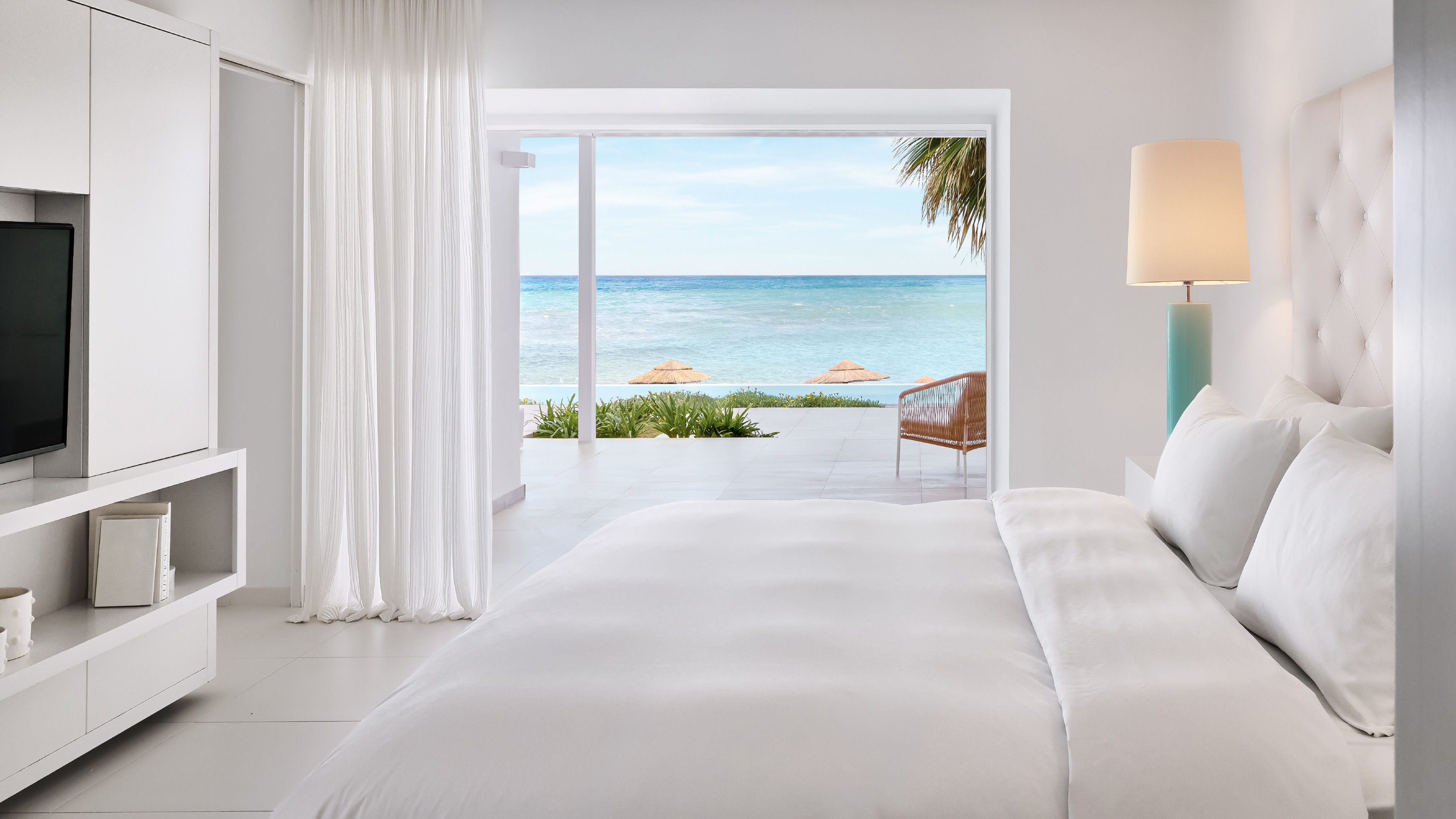 Grecotel LUXME White Crete Yali Seafront Suite bedroom with sea view and outdoor seating.