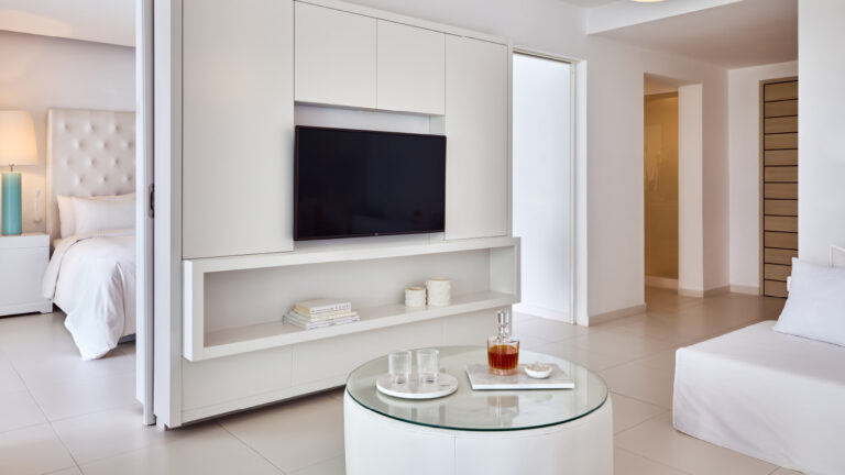 Grecotel LUXME White Crete Yali Seafront Suite living area with TV, sofa and drinks table.