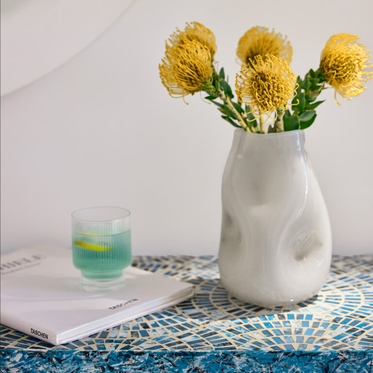 Grecotel LUXME White Crete Open-plan Suite decorative table with flowers and glass.