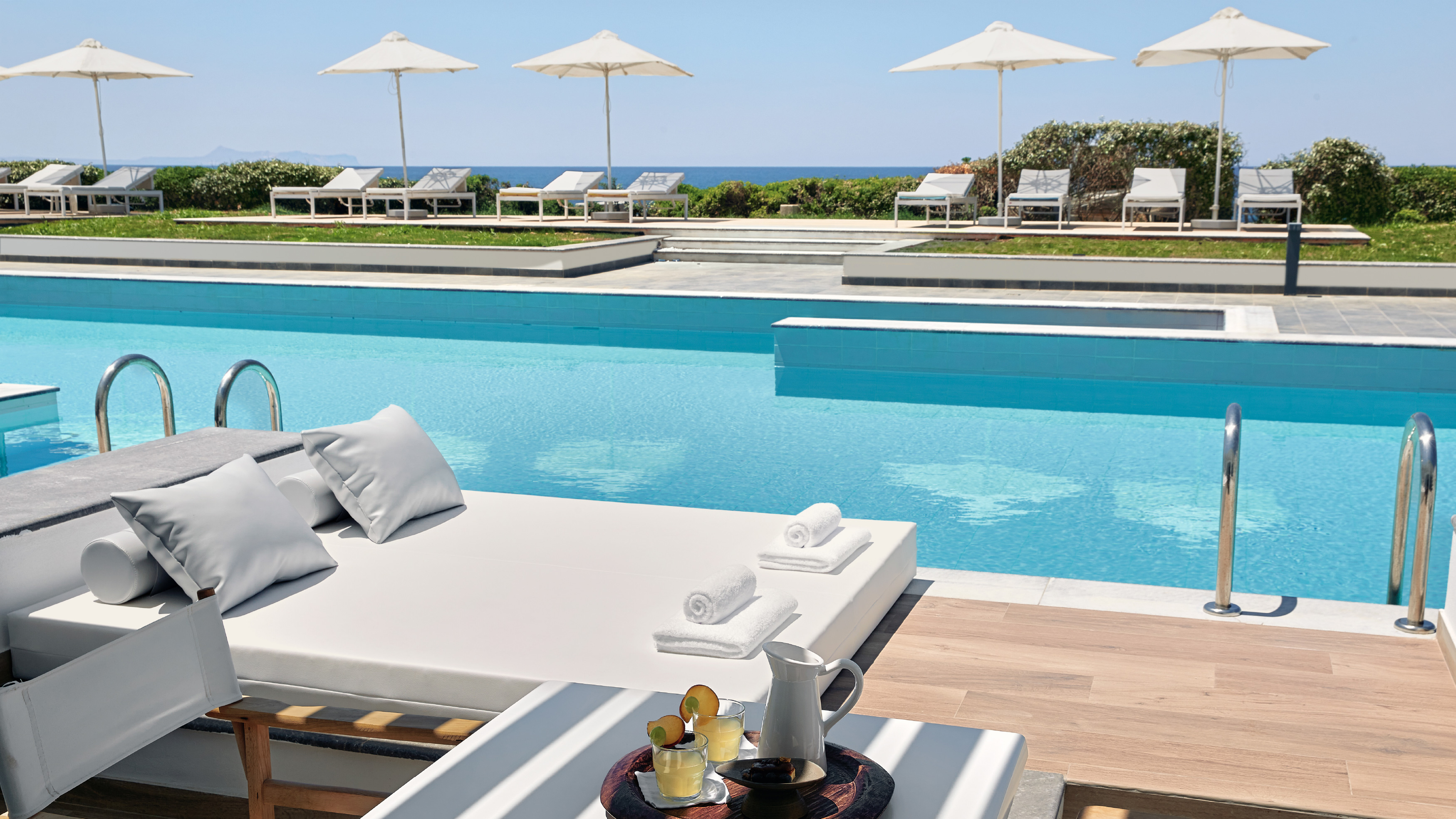 Grecotel LUXME White Crete swim-up pool with sunbeds, umbrellas and sea view