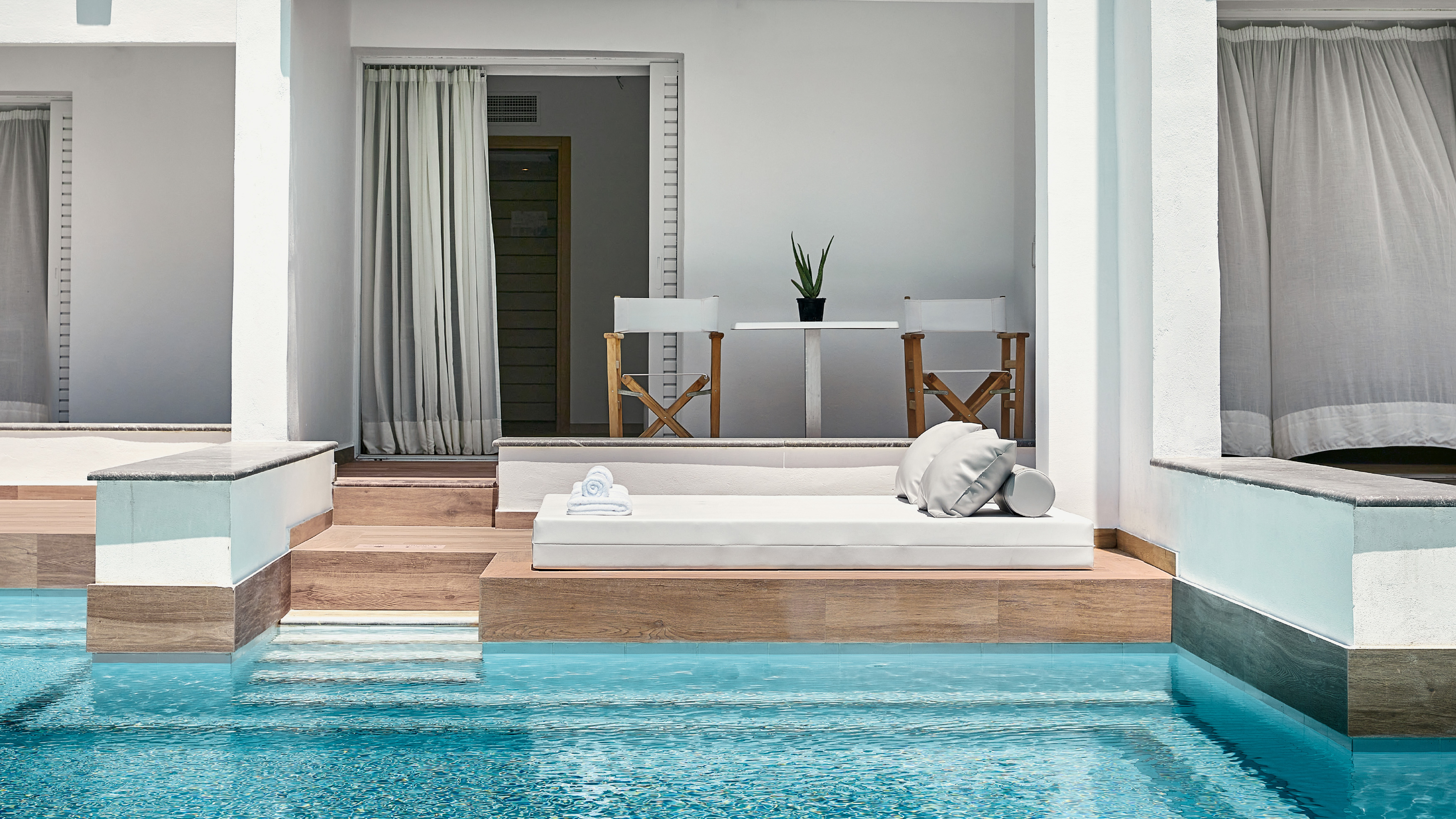 Grecotel LUXME White Crete Swim-up Family Guestroom pool with outdoor daybed and seating area.