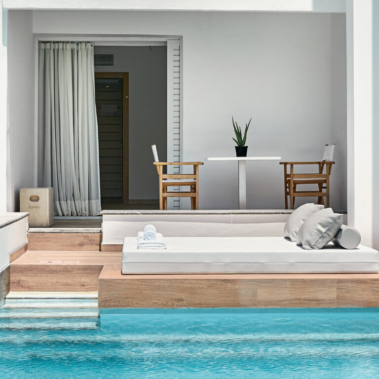Grecotel LUXME White Crete Swim-up Family Guestroom pool with sunbed, palm trees and mountain view.