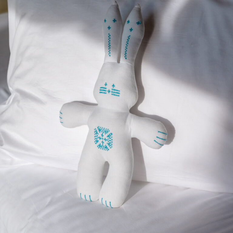 White bunny soft toy on the bed in a Grecotel LUXME White Crete Grand Family Suite.