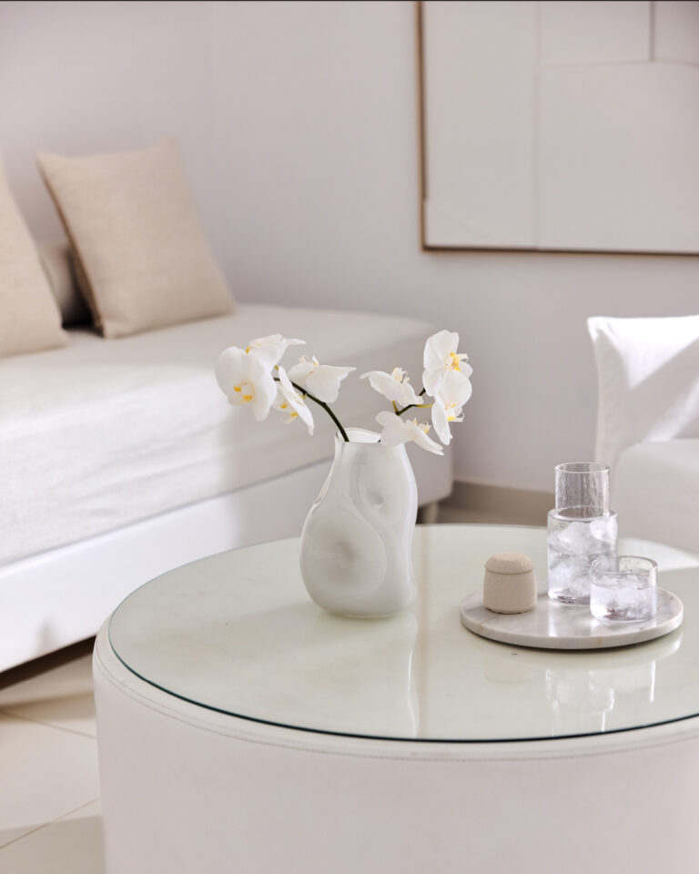 Grecotel LUXME White Crete White Suite living area with flowers and refreshments on a table.