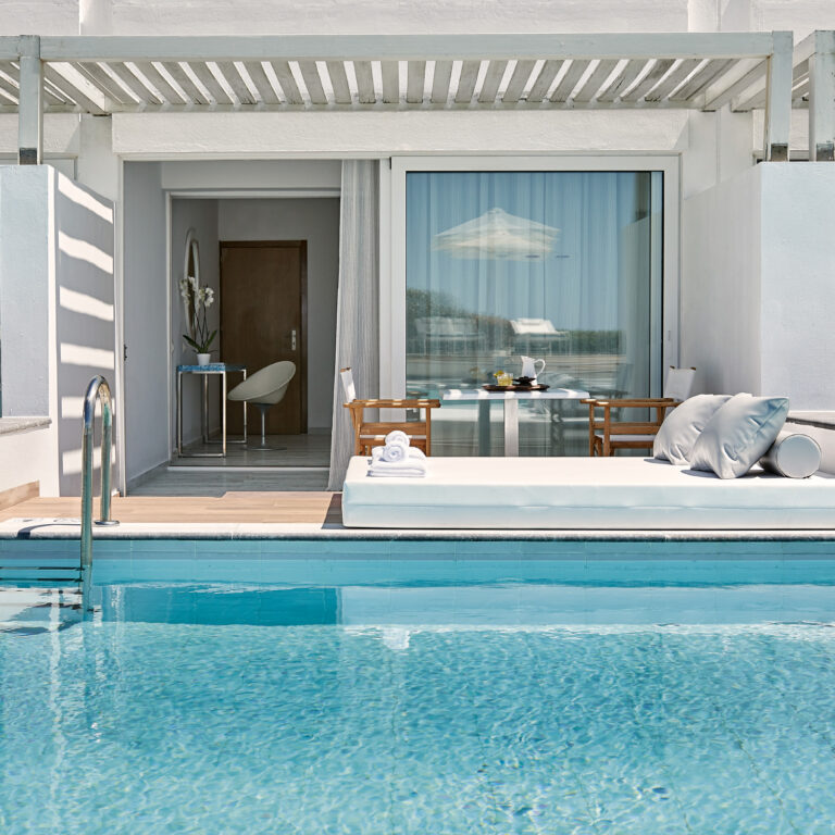 Grecotel LUXME White Crete swim-up guestroom with pool, sunbed and outdoor seating area.