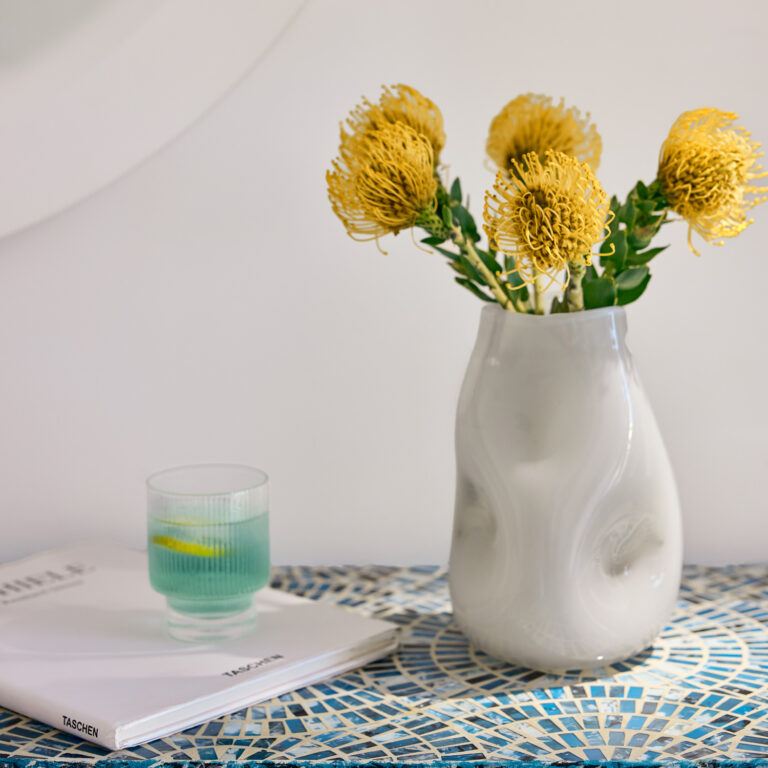 Grecotel LUXME White Crete Family Apartment table with flowers, drink and book.