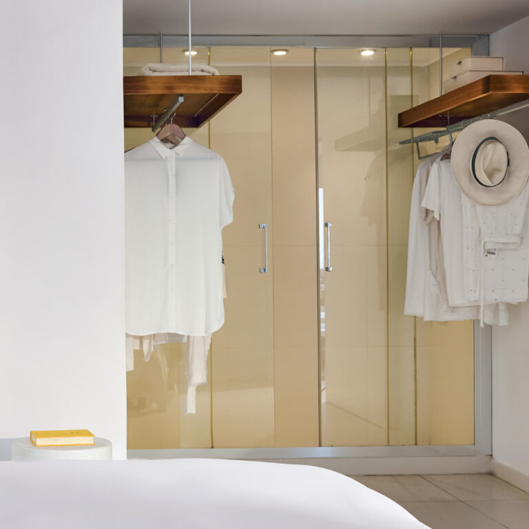 Grecotel LUXME White Crete White Family Suite wardrobe with hanging clothes and hat.