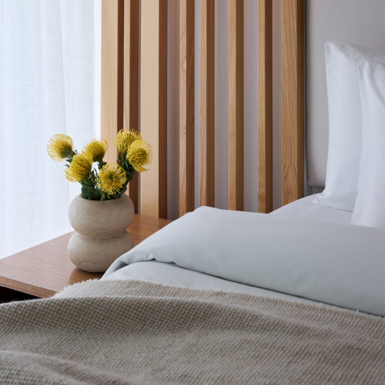 Grecotel LUXME White Crete Villa Luxe Yali bedroom with yellow flowers beside the bed.
