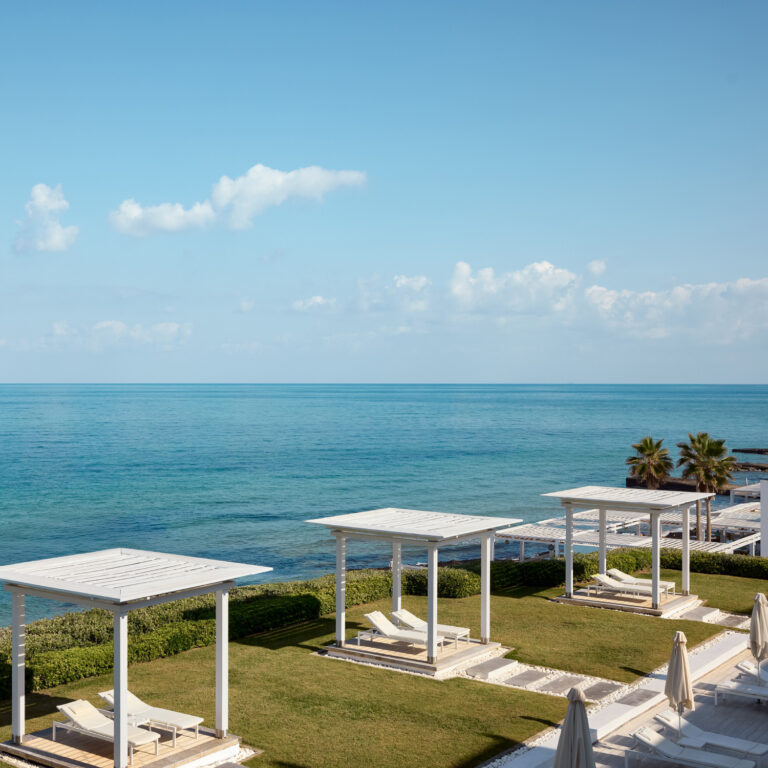Grecotel LUXME White Crete sea view with cabanas, loungers and gardens.
