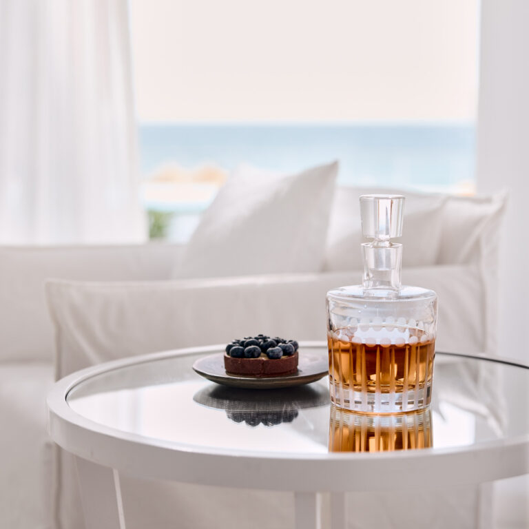 Dessert and drink on a table with sea view in a Grecotel LUXME White Crete Petit Yali Seafront Suite.