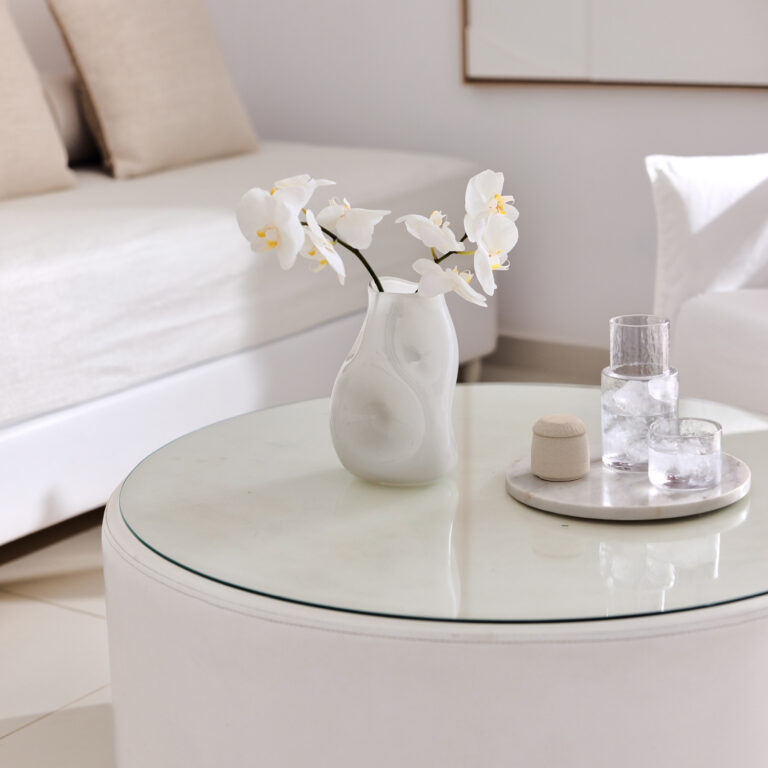 Grecotel LUXME White Crete Yali Seafront Suite table with white orchids and glasses of water.