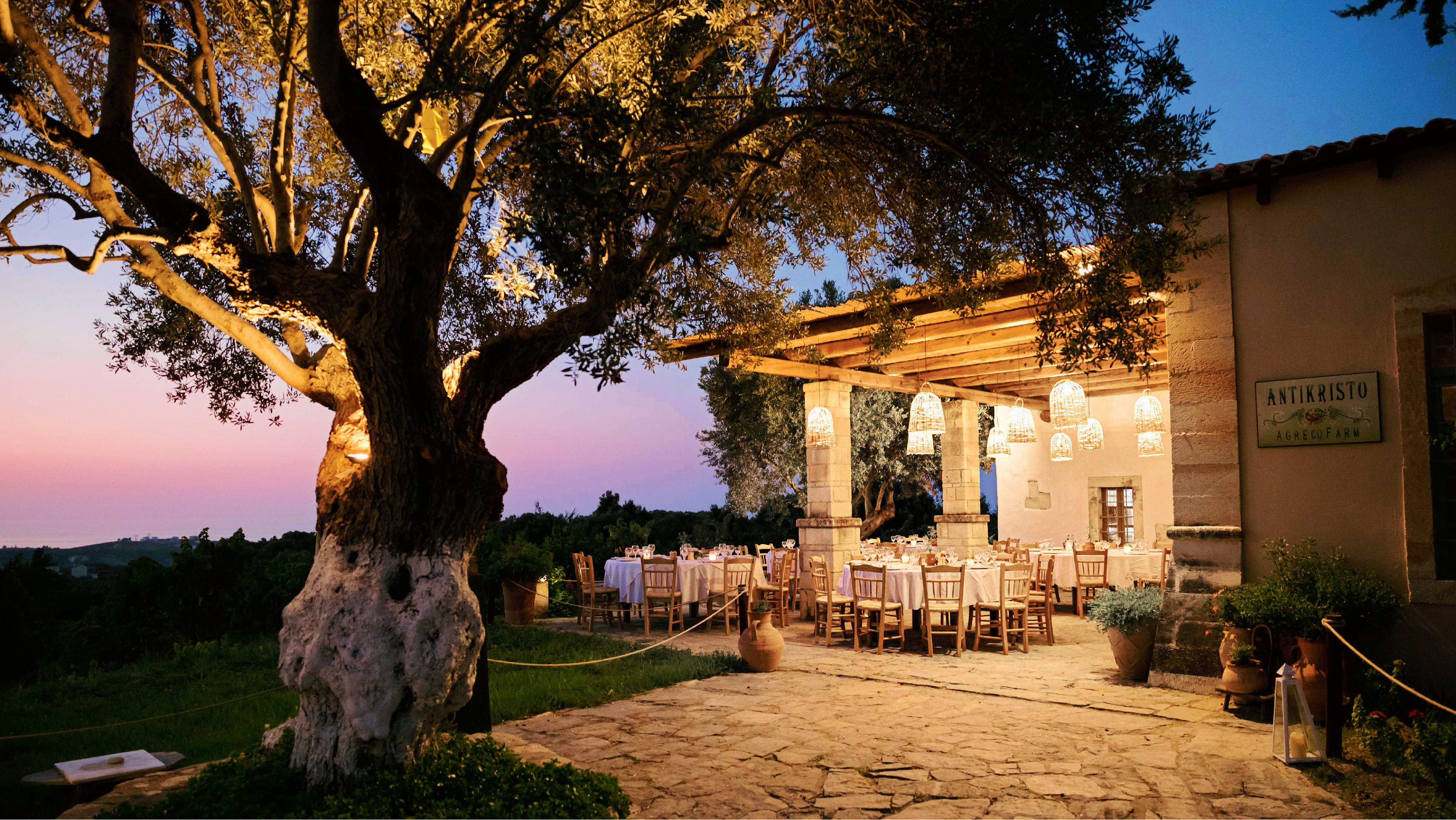 Grecotel Agreco Farm Antikristo taverna with outdoor dining at sunset.