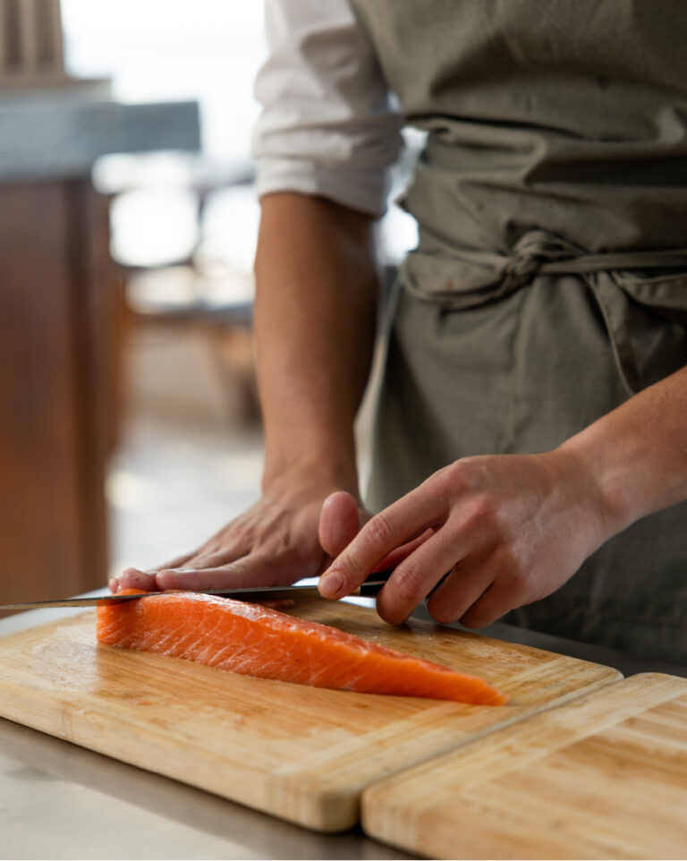 Chef preparing fresh salmon as part of the dining offer at Grecotel LUXME White Crete.