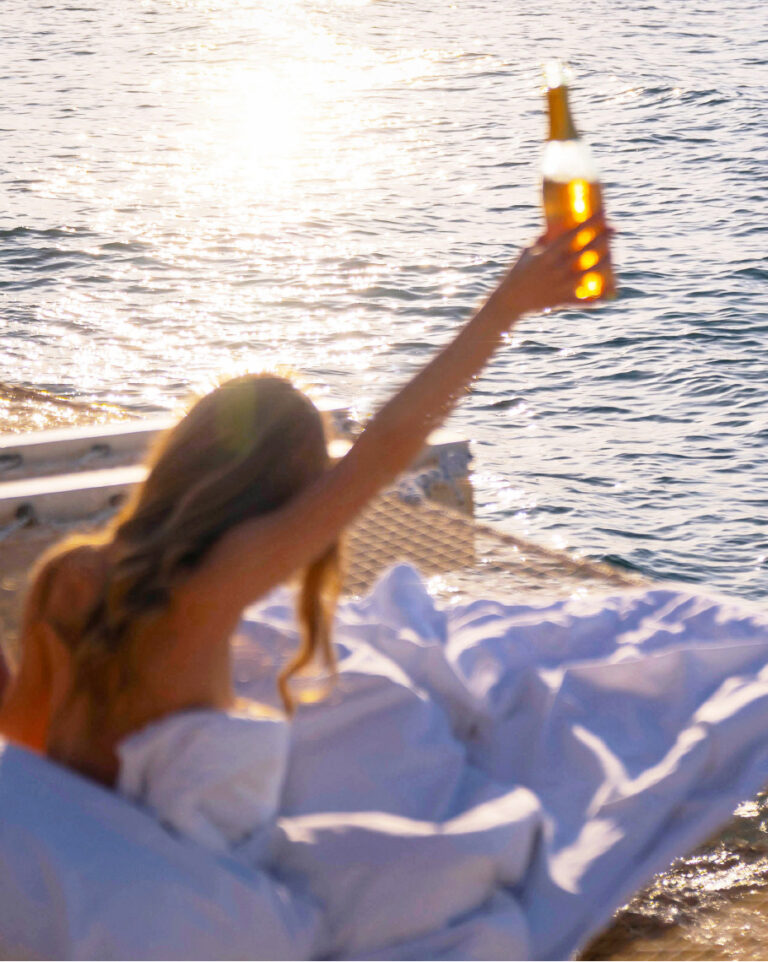 Guest raising a bottle of wine beside the sea at Grecotel LUXME White Crete.