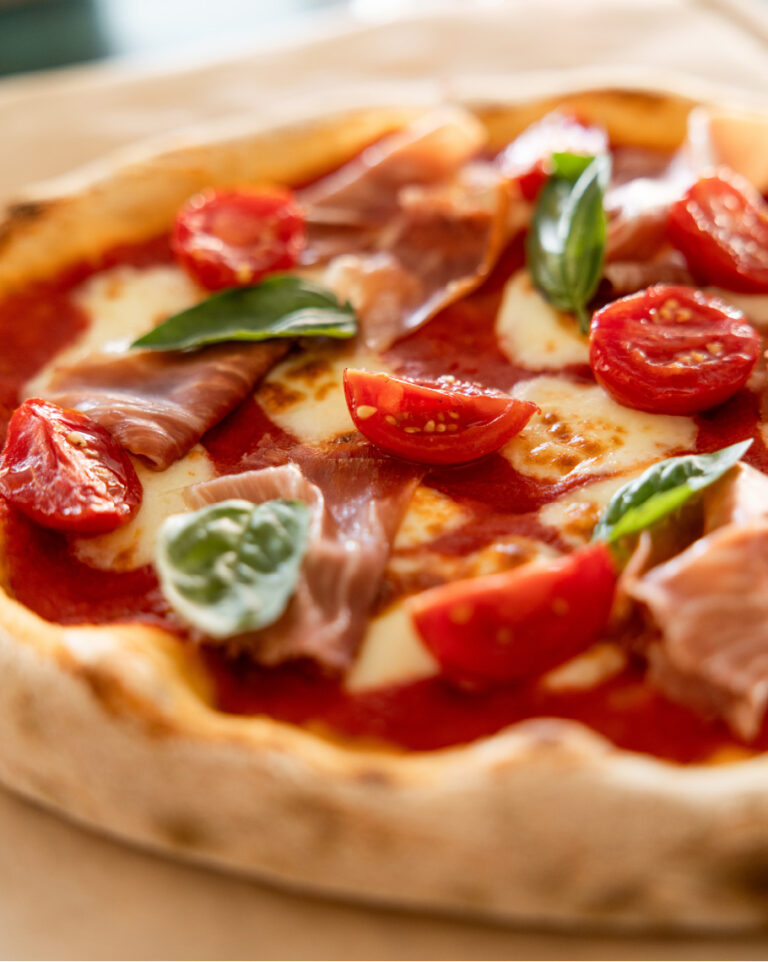 Pizza with prosciutto, tomatoes and basil at Grecotel LUXME White Crete.