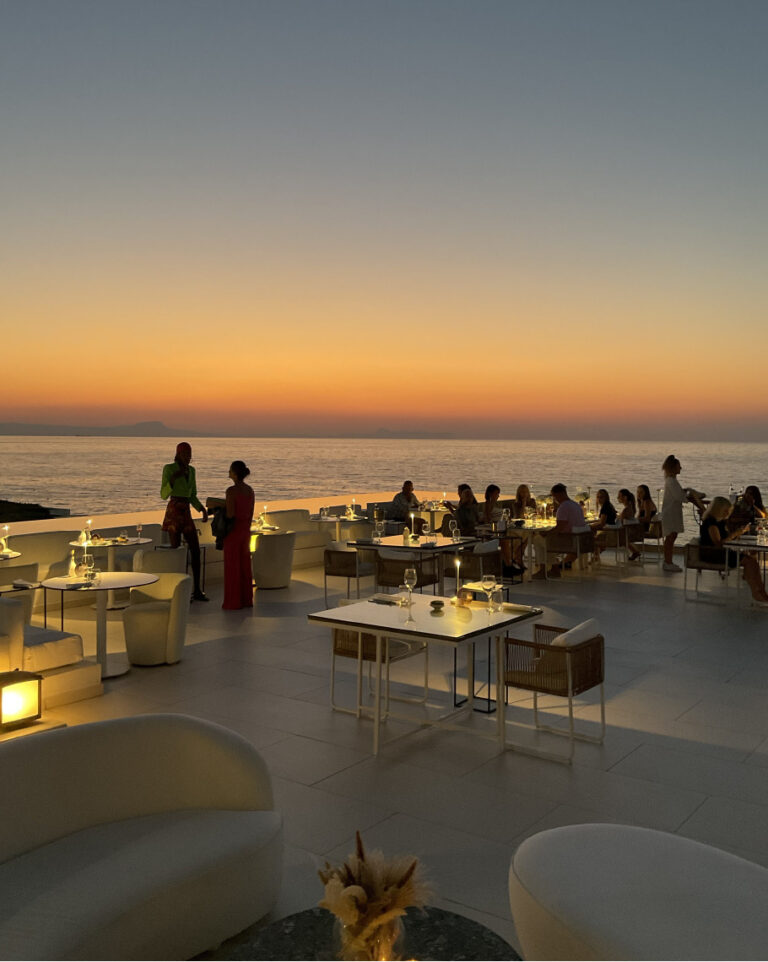 Guests dining at an adults-only restaurant overlooking the sea at sunset at Grecotel LUXME White Crete.