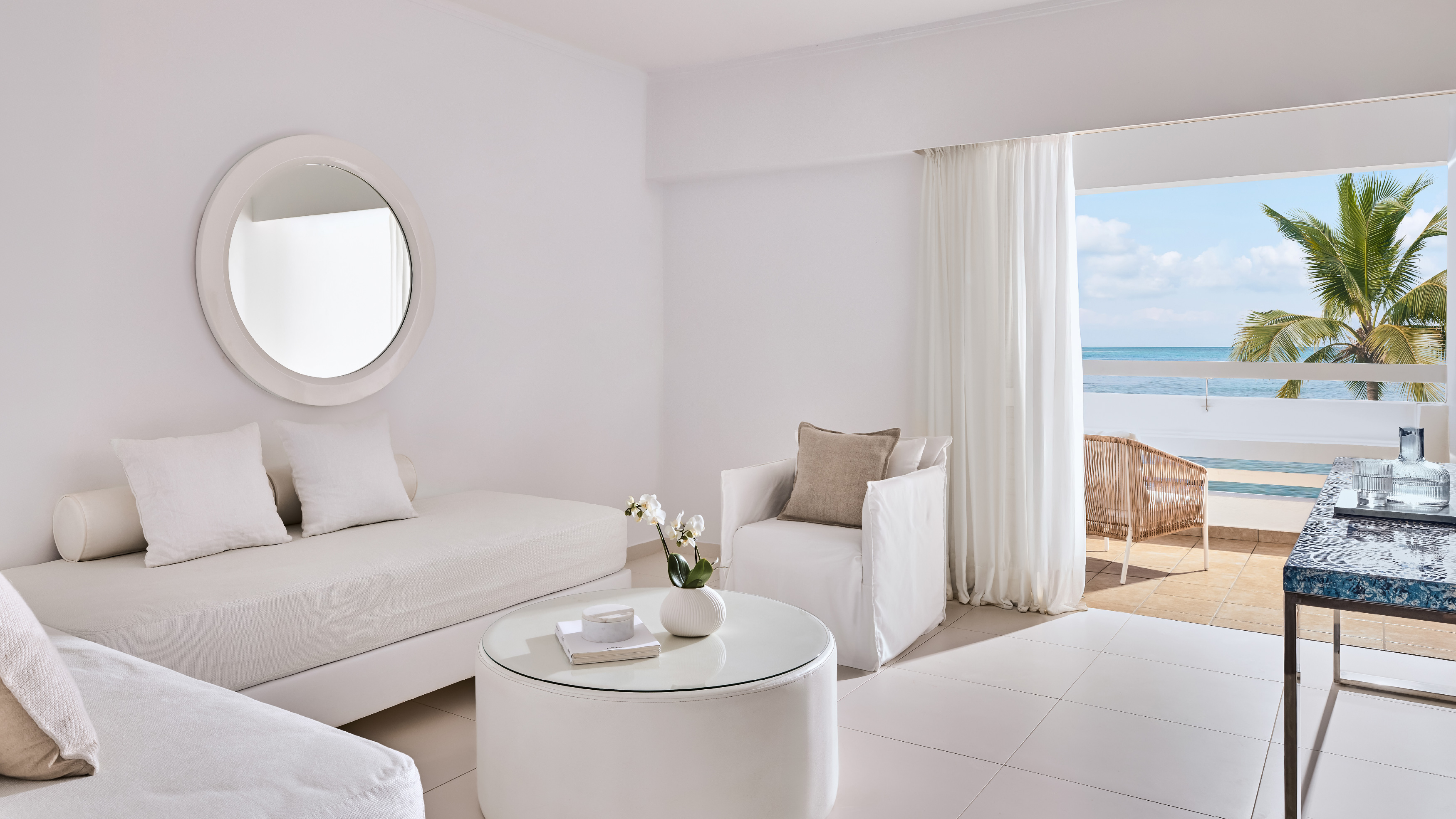 Grecotel LUXME White Crete White Suite living area with sofa, armchair and sea view.