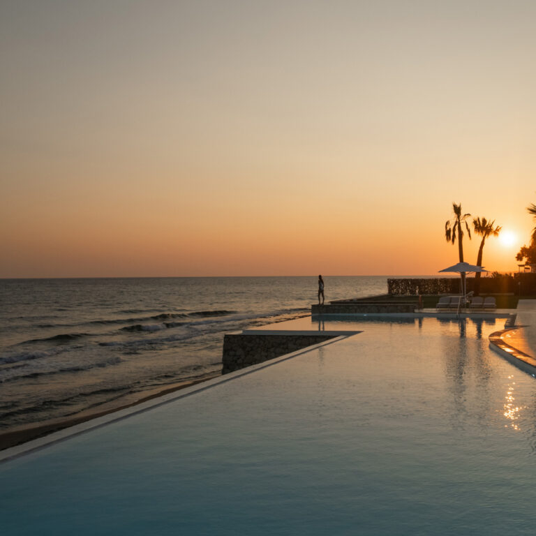Grecotel LUXME White Crete infinity pool and sea at sunset.