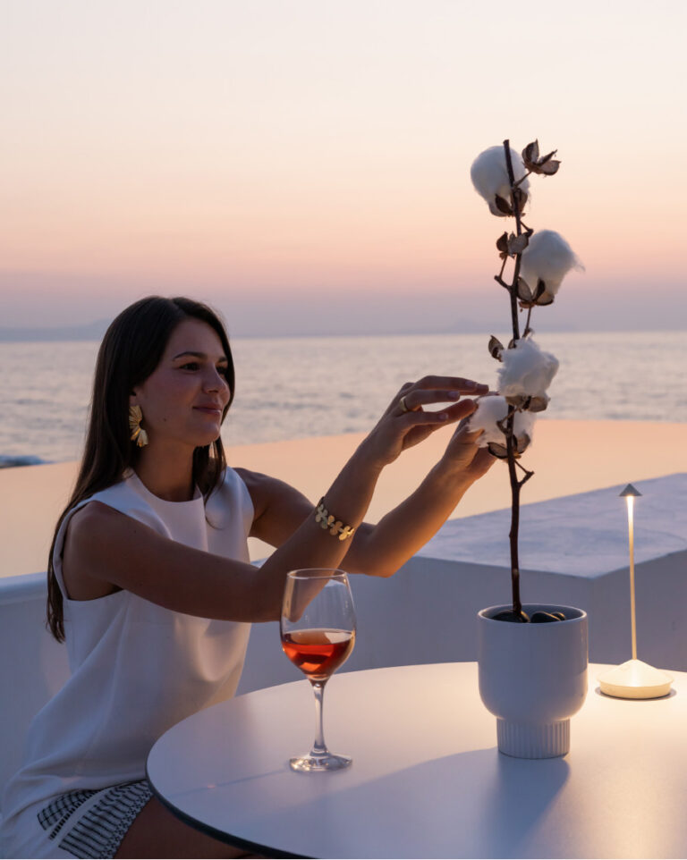 Guest with a glass of wine at The White Restaurant overlooking the sea at Grecotel LUXME White Crete.
