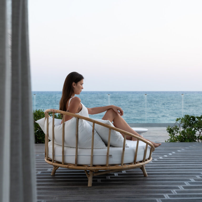 Woman relaxing in an outdoor chair overlooking the sea at Grecotel LUXME White Crete Villa Luxe Yali.