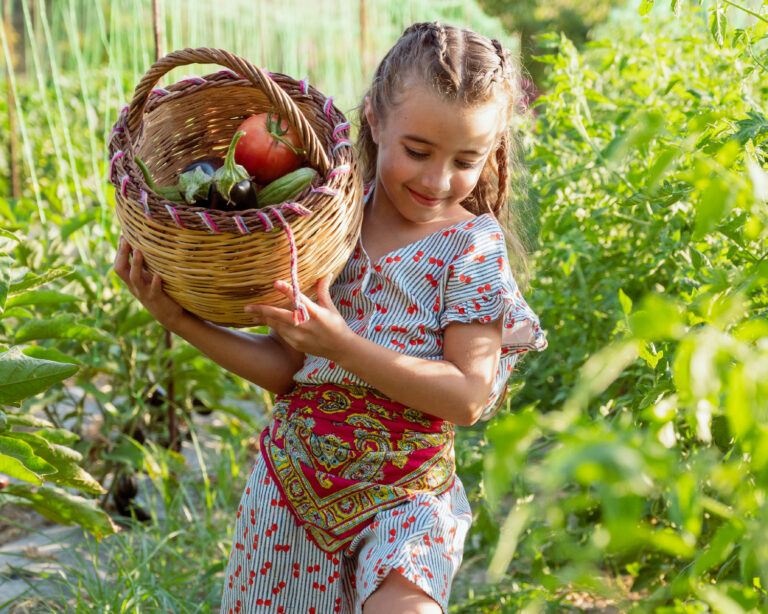 Child carrying a basket of vegetables at Agreco Farm in Crete.