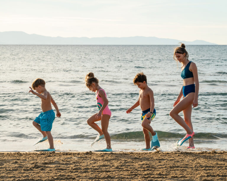 Children walking along the beach with a caregiver at Grecotel LUXME White Crete.