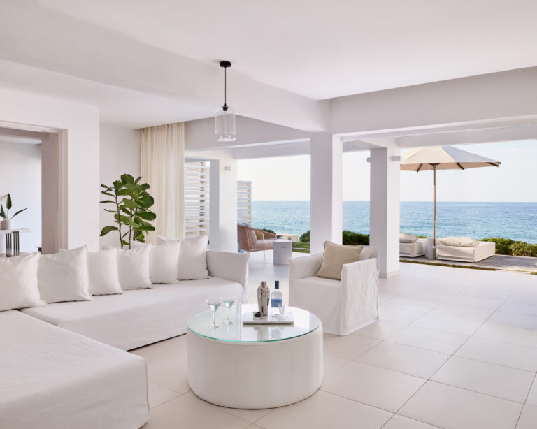 Grecotel LUXME White Crete villa living area with sofa, armchairs and sea view.