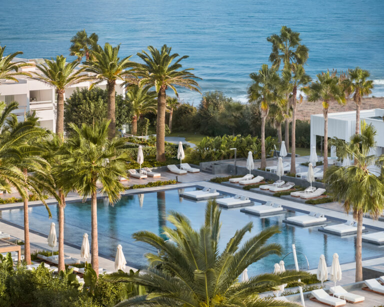 Grecotel LUXME White pools, palm trees and beach overlooking the sea.