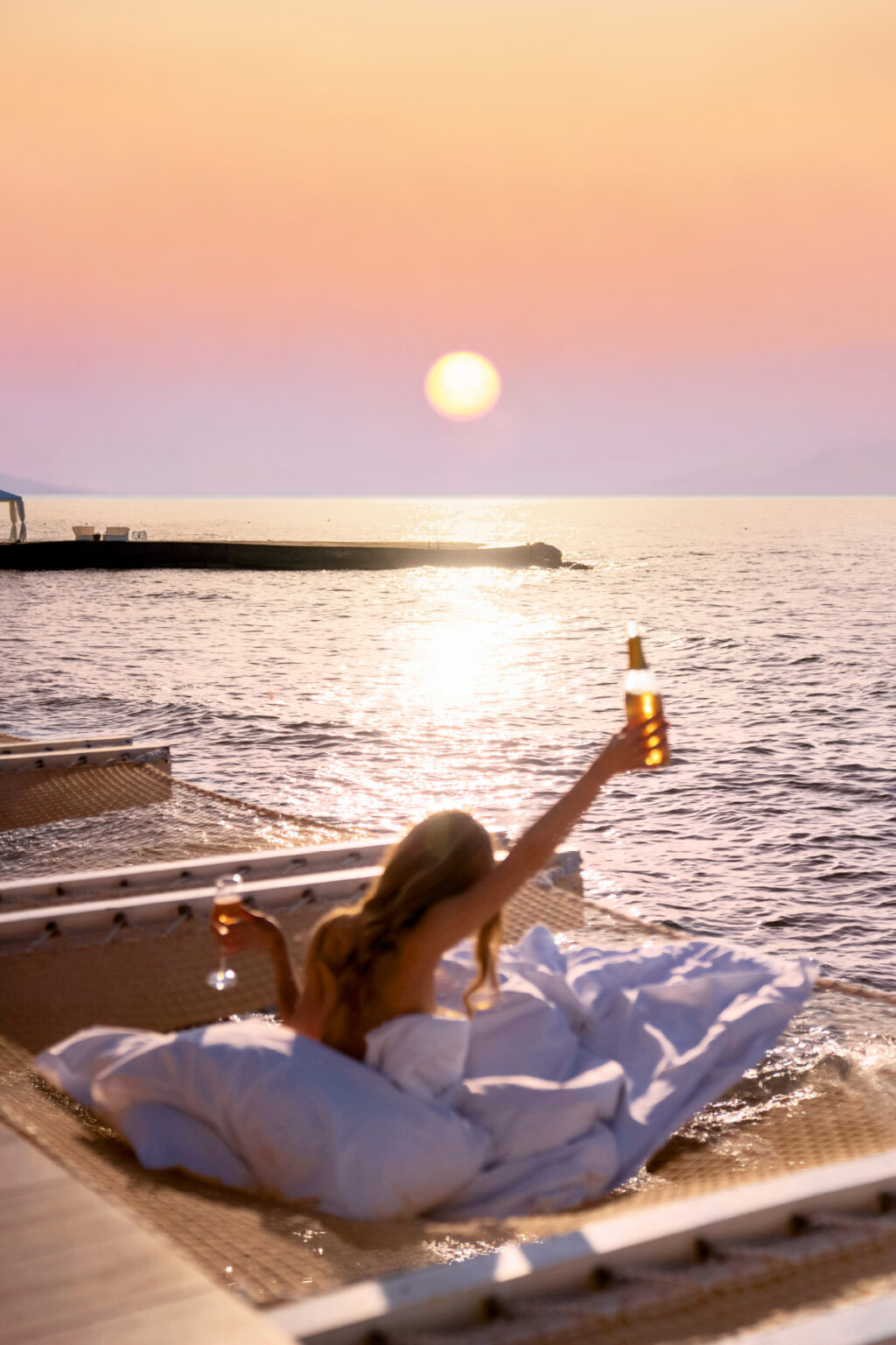 Guest relaxing by the sea at sunset at Grecotel LUXME White.