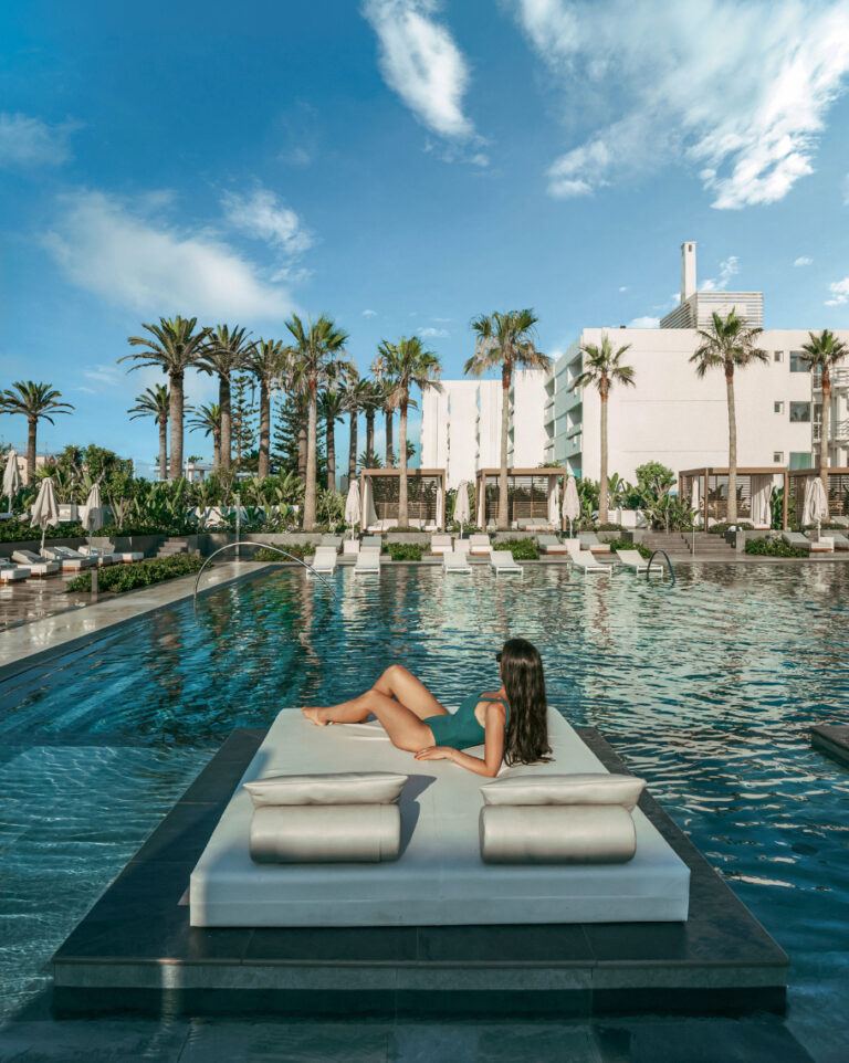 Woman relaxing on a pool daybed at Grecotel LUXME White.