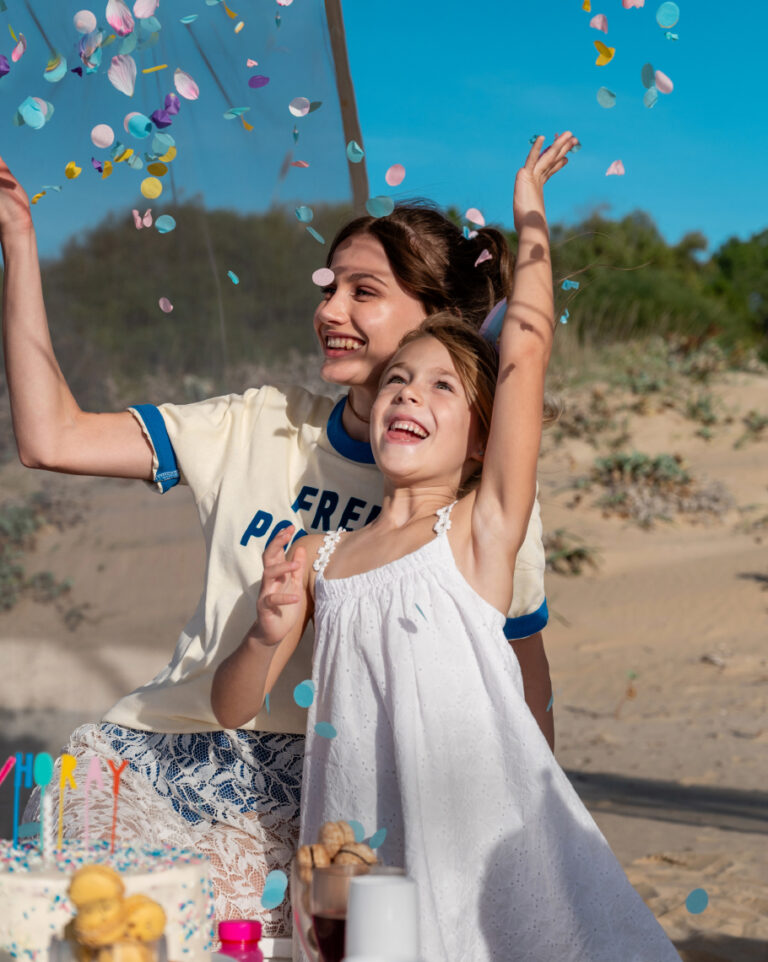 Family celebrating with cake and confetti at Grecotel LUXME White.